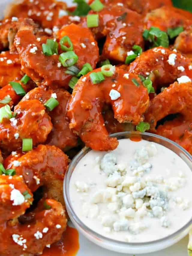 One plate of buffalo shrimp with blue cheese dressing dip and sliced lemons