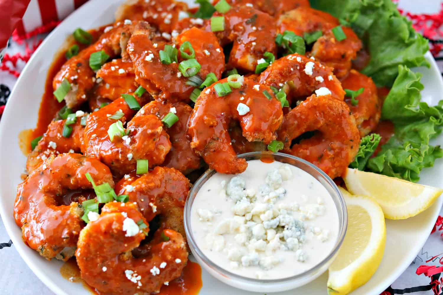 One plate of buffalo shrimp with blue cheese dressing dip and sliced lemons