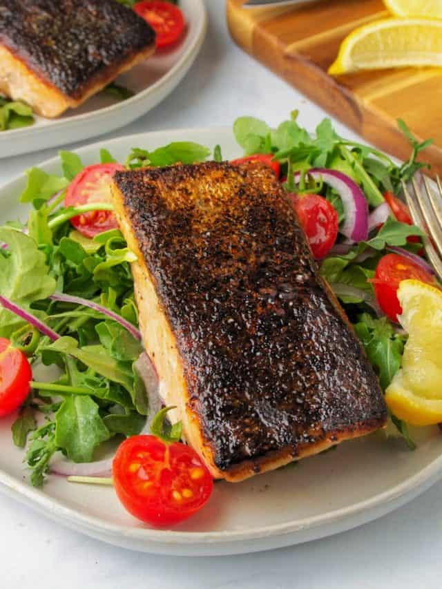 crispy skin salmon on a plate with a side salad and a wedge of lemon
