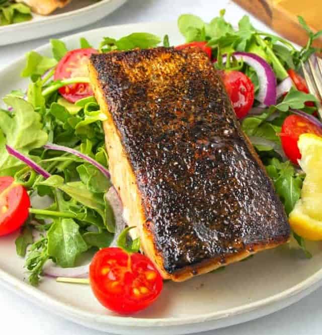 One plate of crispy skin salmon topped in a veggie salad