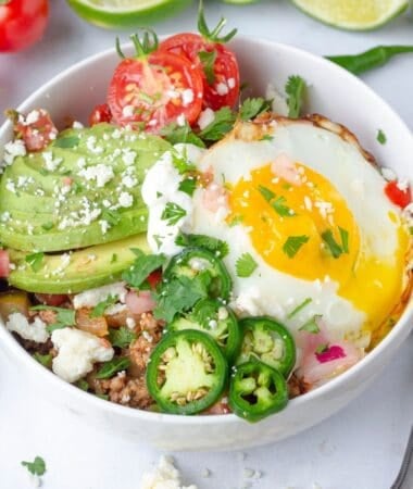 a breakfast taco bowl with a sunny side up egg and other toppings