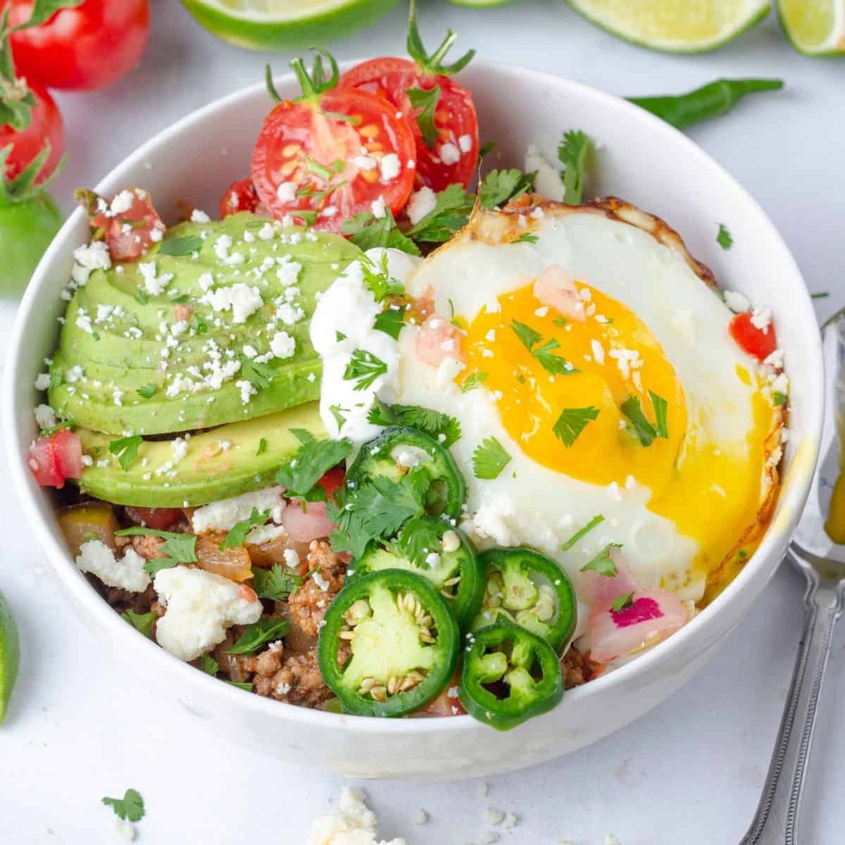 a breakfast taco bowl with a sunny side up egg and other toppings