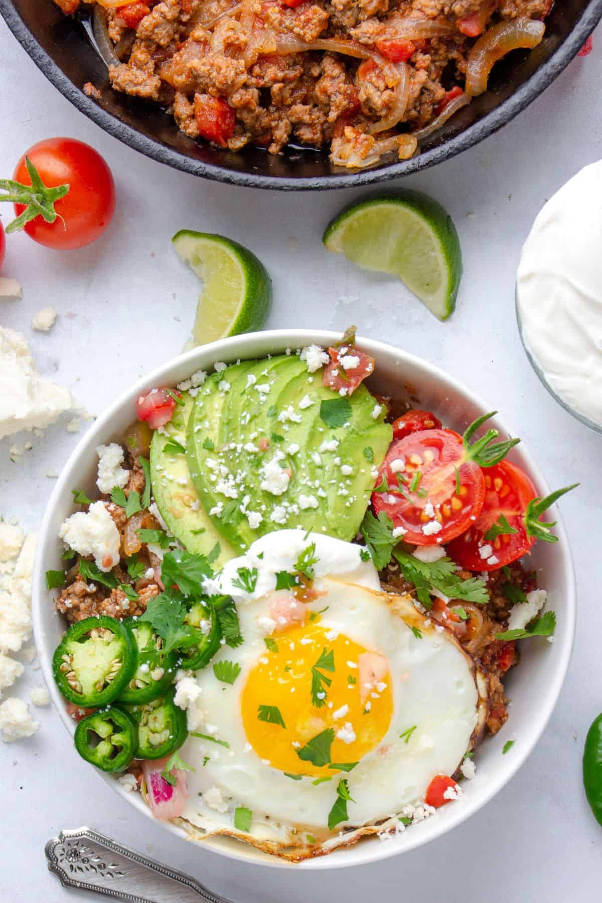 breakfast taco bowl in the process of being built with toppings