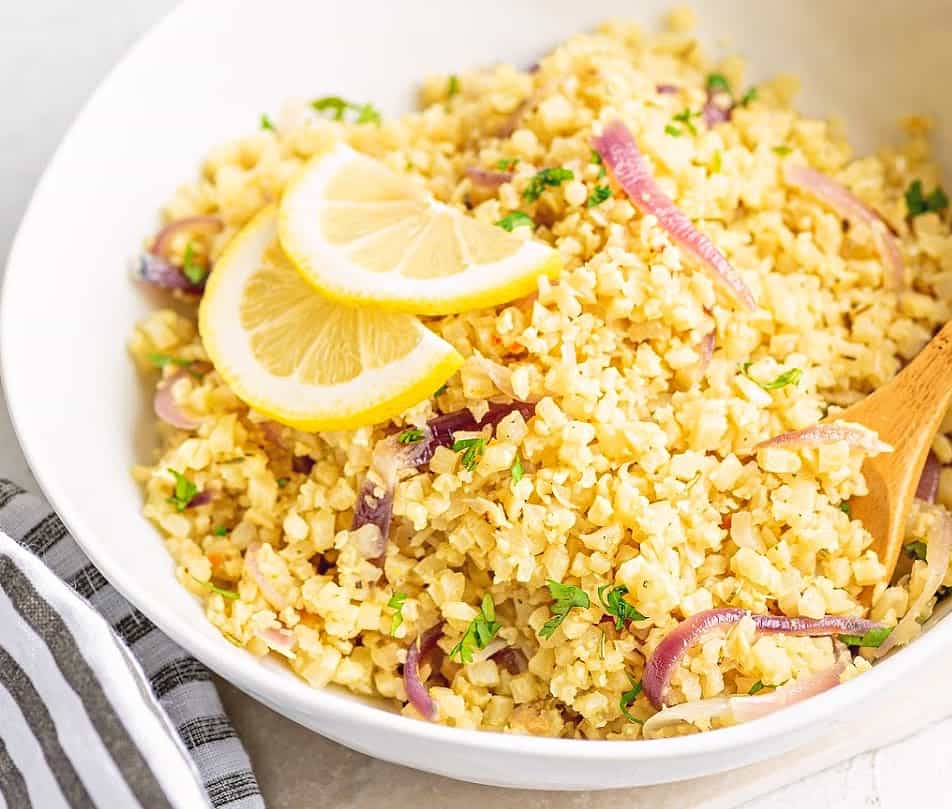 One bowl of Cauliflower Rice Pilaf with sliced lemons
