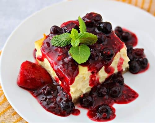 low carb cheesecake on a plate topped with a mixed berry sauce