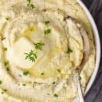 a close-up of a bowl of roasted cauliflower mash in a bowl with herbs and butter