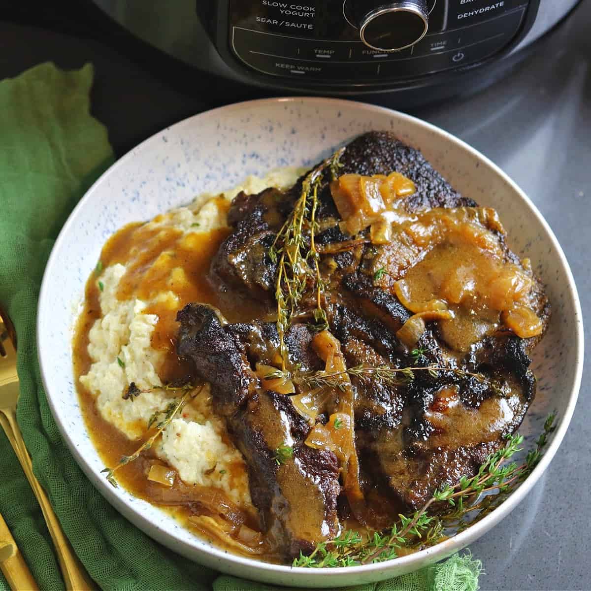 close-up of Ninja Foodi Pot Roast with Gravy in a bowl with cauliflower mashed potatoes