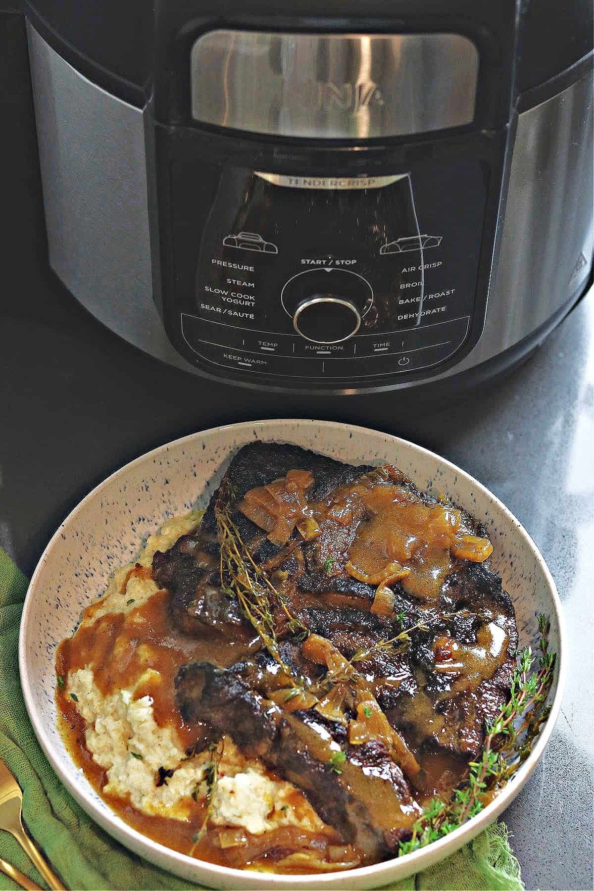 Ninja Foodi pot roast on a plate with gravy and mashed cauliflower