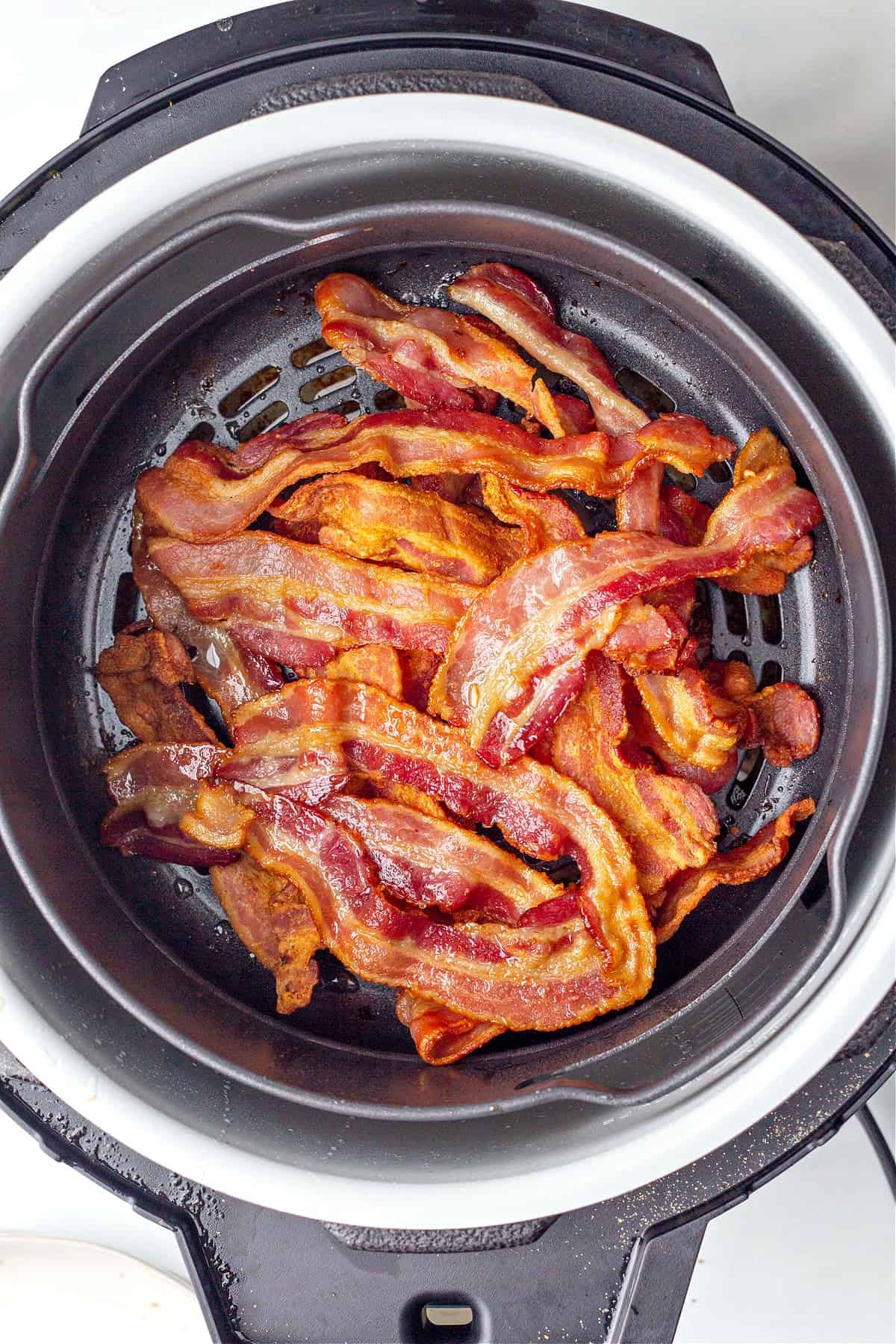Overhead view of a pile of cooked bacon in an air fryer