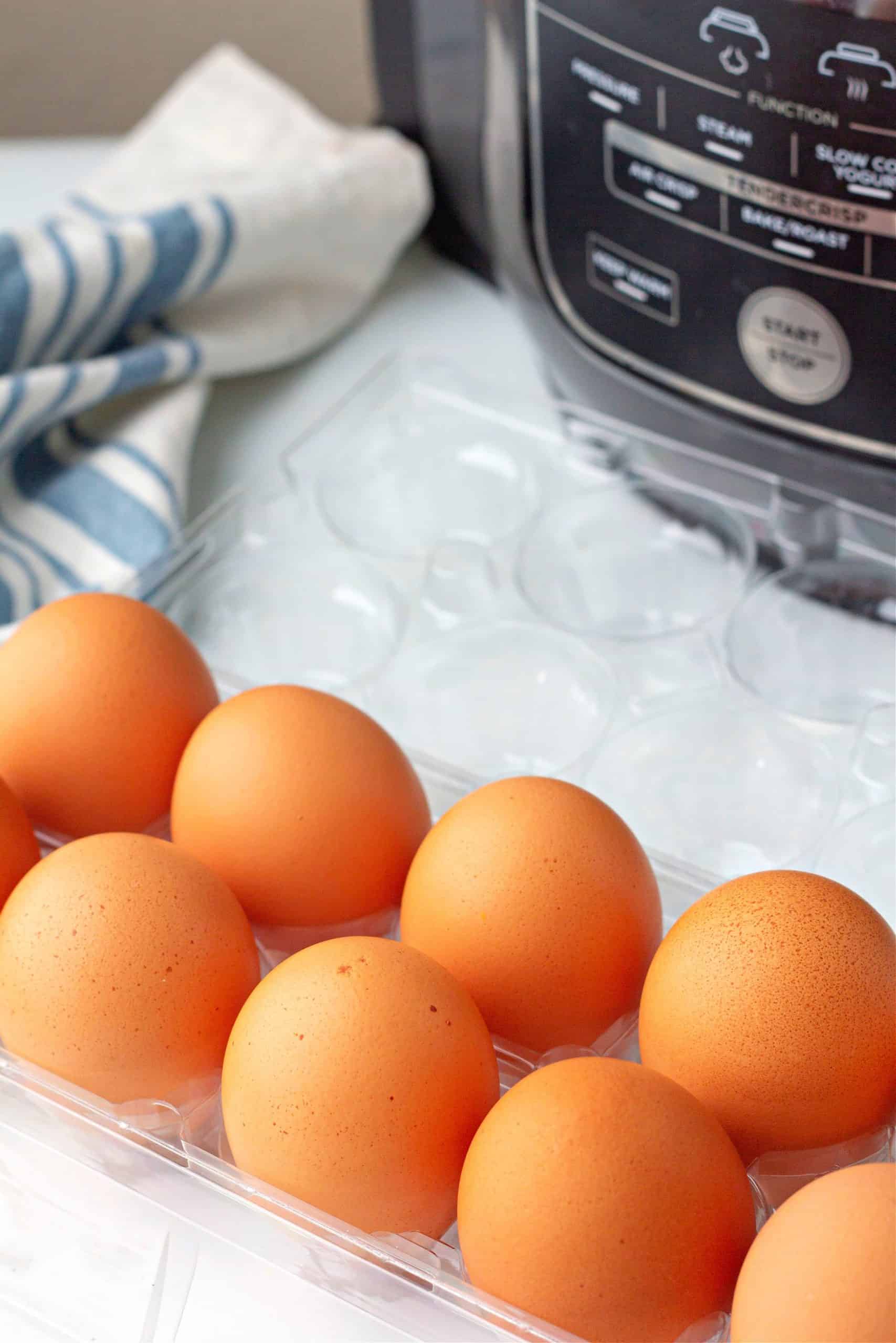 ingredients needed to make ninja air fryer hard boiled eggs like a dozen eggs in front of a ninja foodi air fryer