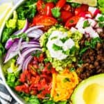 keto taco salad in a bowl with avocado, Pico De Gallo, taco meat, cheddar, lettuce, and red onions