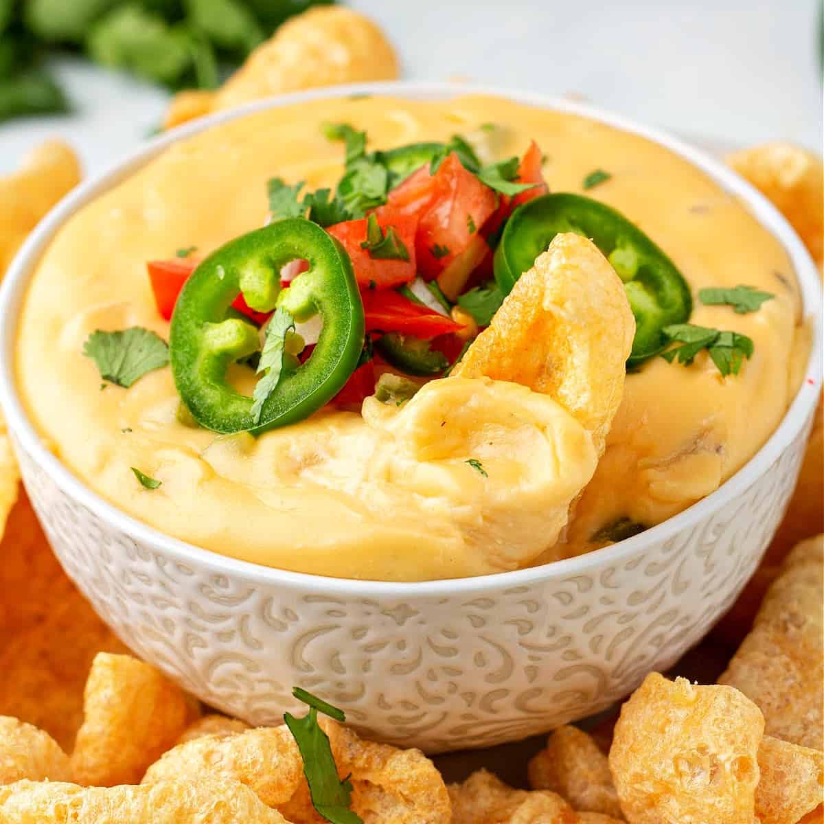 a close up of homemade keto queso cheese dip with pork rinds in a bowl