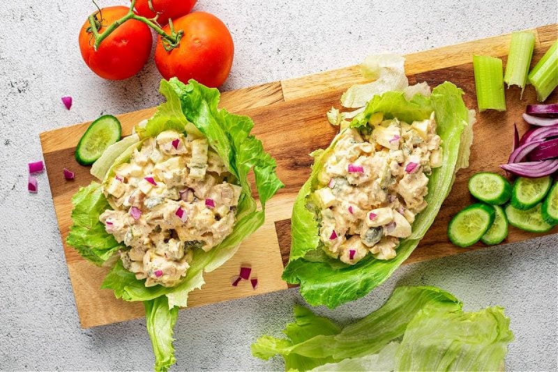 two tuna salad lettuce wraps on a cutting board with tomatoes