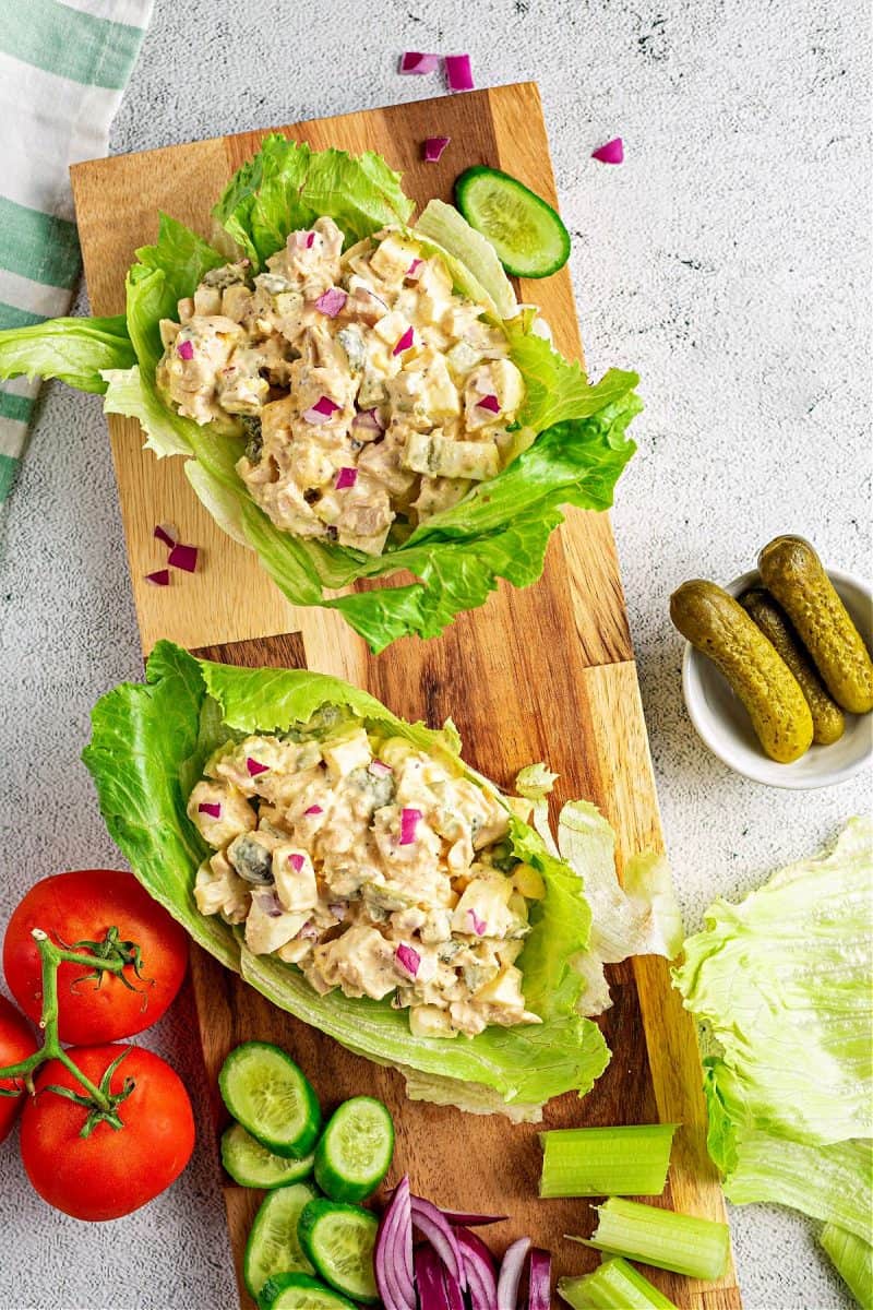 a close-up of two keto tuna salad lettuce wraps on a cutting board with chopped vegetables
