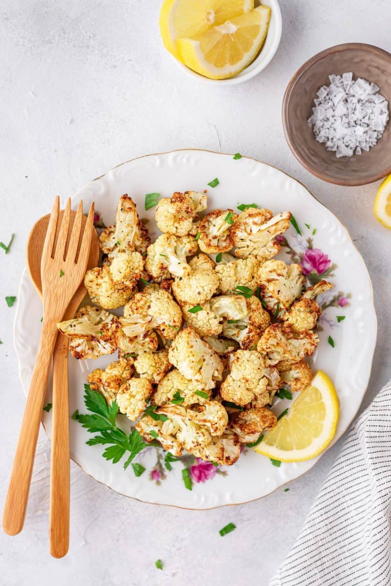 roasted cauliflower on a plate with herbs, lemon and sea salt