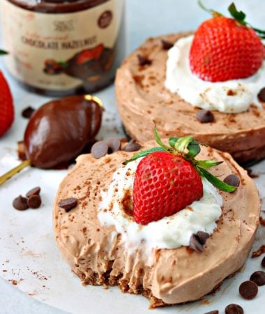 two keto chocolate cheesecakes on a parchment paper with keto Nutella chocolate hazelnut spread on a spoon