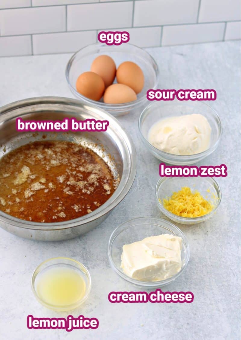 keto lemon cake wet cake ingredients with text to label the eggs, sour cream, cream cheese, browned butter, lemon juice and lemon zest