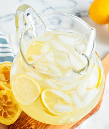 a pitcher of keto lemonade on a wooden board with sliced lemons