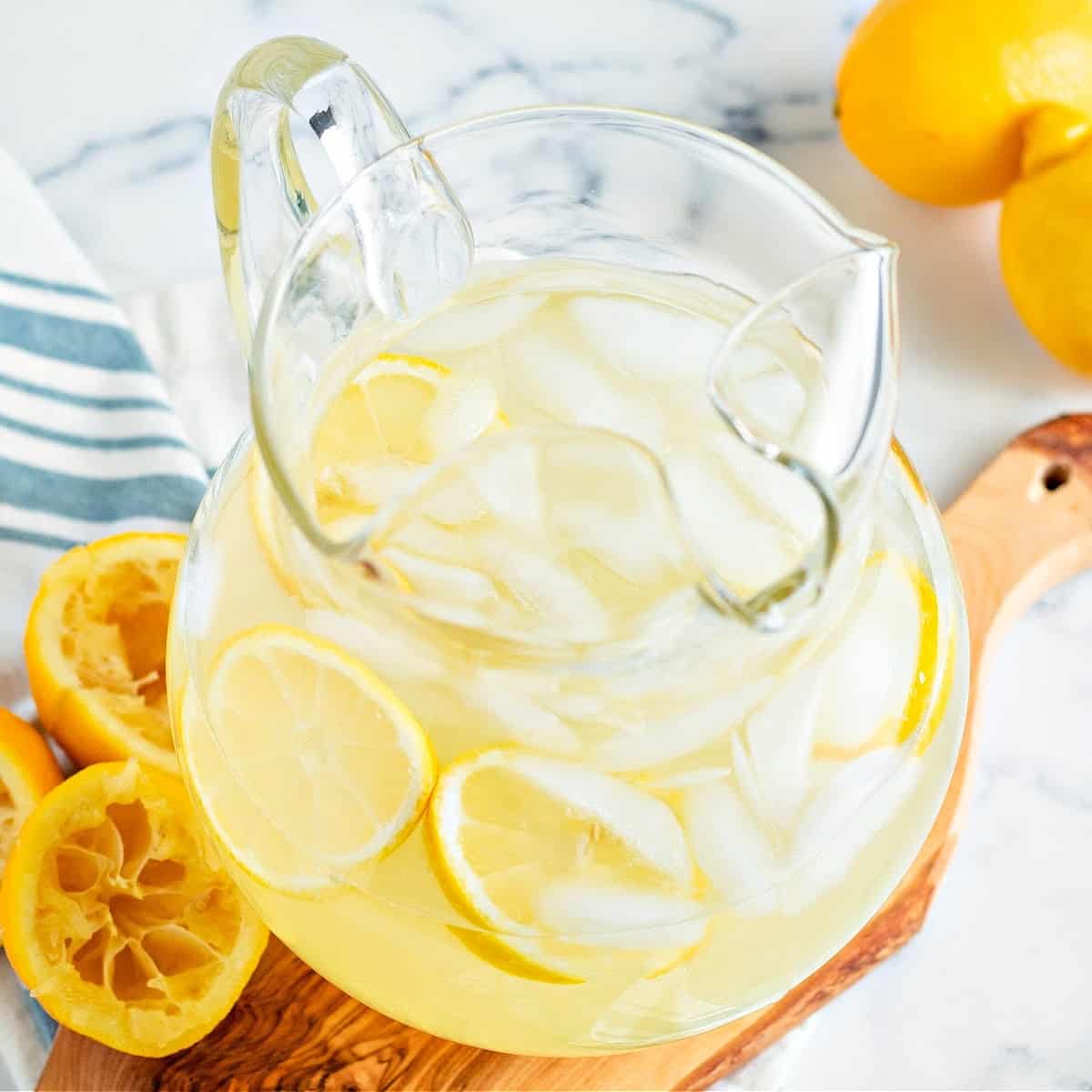 a pitcher of keto lemonade on a wooden board with sliced lemons