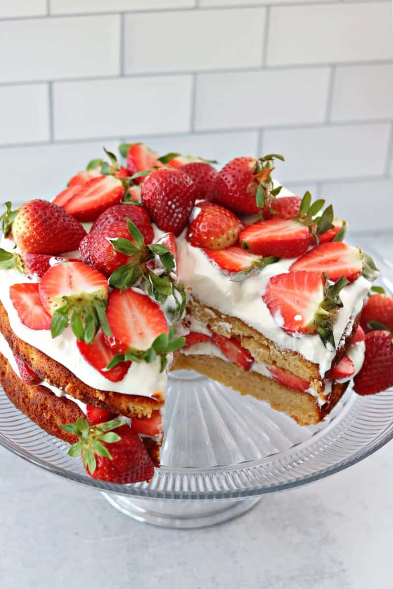 double layer low carb strawberry shortcake on a cake stand with a slice cut out
