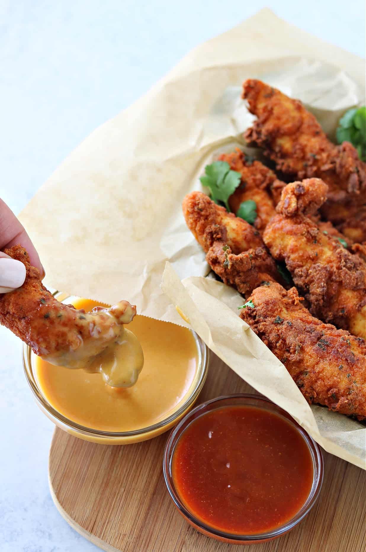 crispy chicken tender being dipped in copycat chick-fil-a sauce