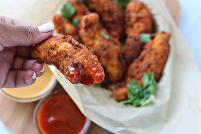 a close-up of a keto chicken tender dipped in keto bbq sauce