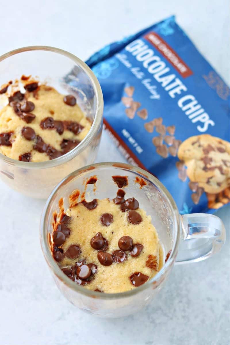 two keto peanut butter mug cakes in glass mugs with choczero milk chocolate chips on top