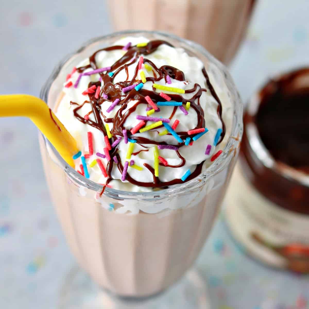 an overhead view of keto nutella frosty in a glass mug with keto whipped cream and sprinkles on top