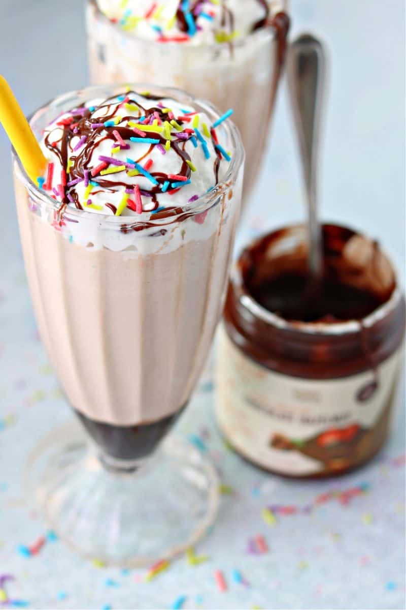 close-up with keto frosty in a glass milkshake cup topped with sprinkles and keto whipped cream