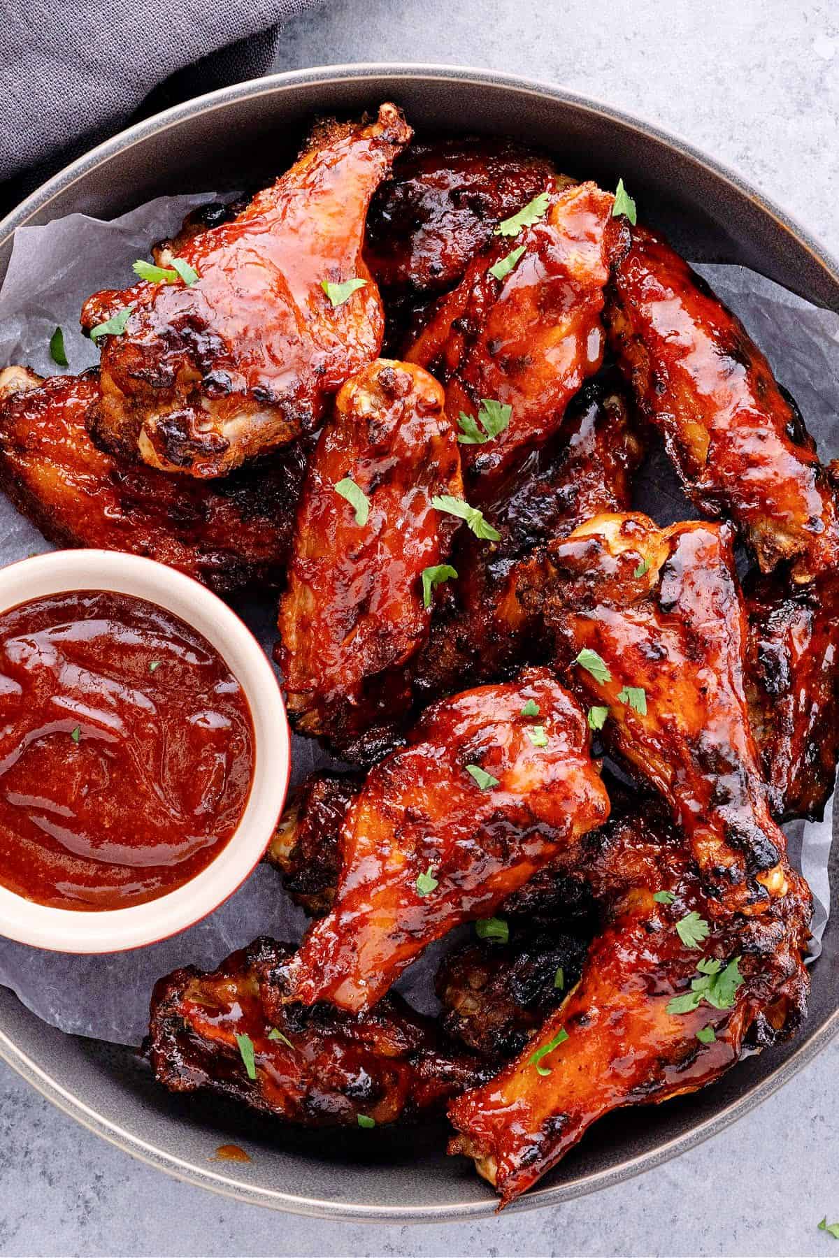 air fryer bbq chicken wings in a metal pan with a side of keto bbq sauce