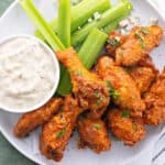 keto buffalo wings on a white plate with homemade blue cheese dressing and celery