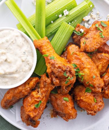 keto buffalo wings on a white plate with homemade blue cheese dressing and celery
