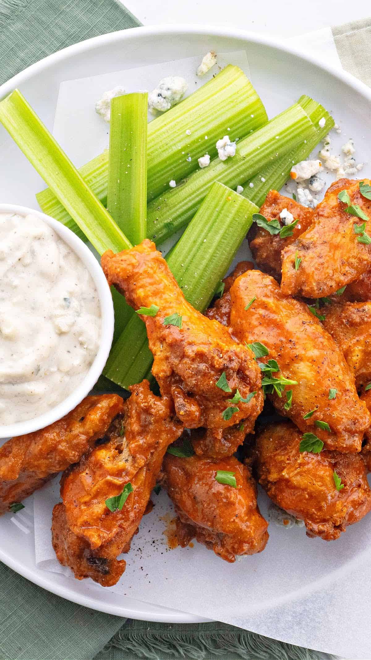 a plate of air fryer buffalo wings with blue cheese dressing and celery sticks