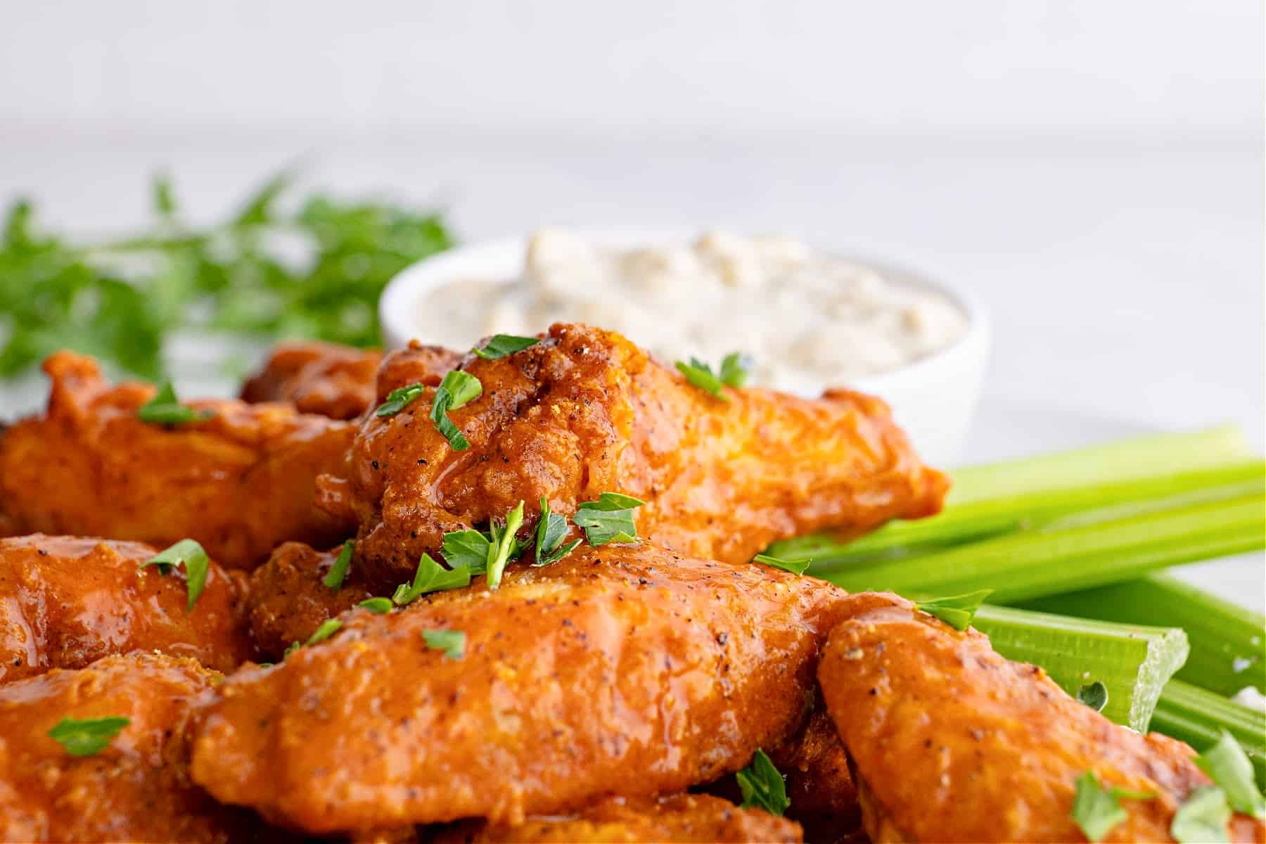 a plate of air fryer buffalo wings with celery, parsley, and blue cheese dressing