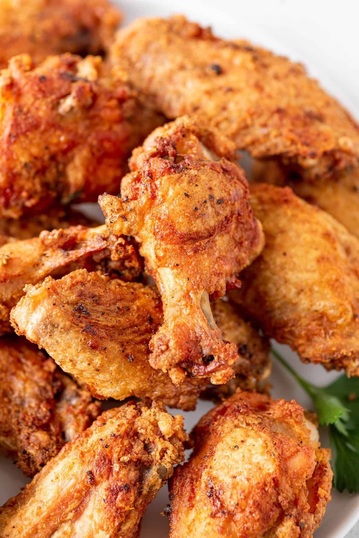 Close up of a baked chicken wing on top of a pile of wings.