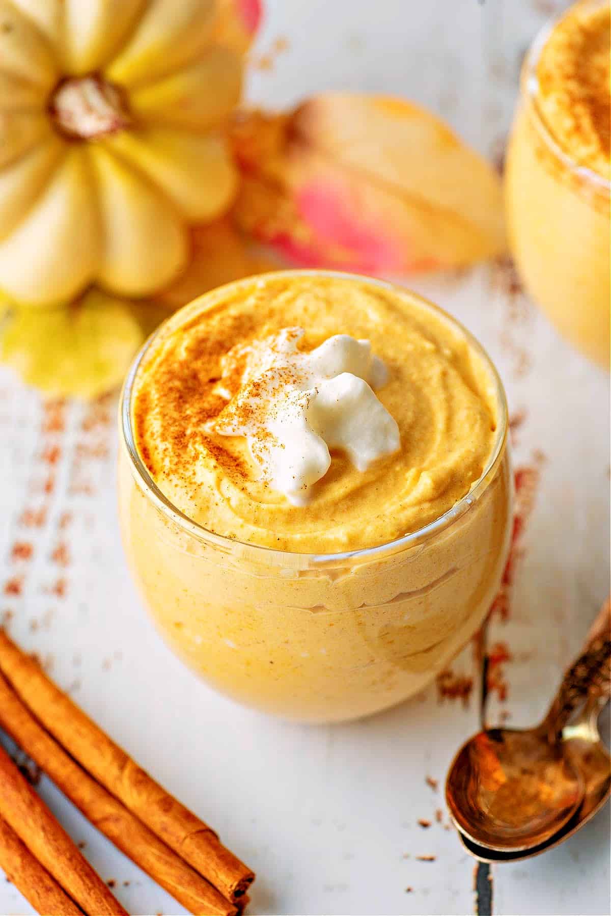 kto pumpkin mousse in a glass cup with whipped cream and cinnamon sticks