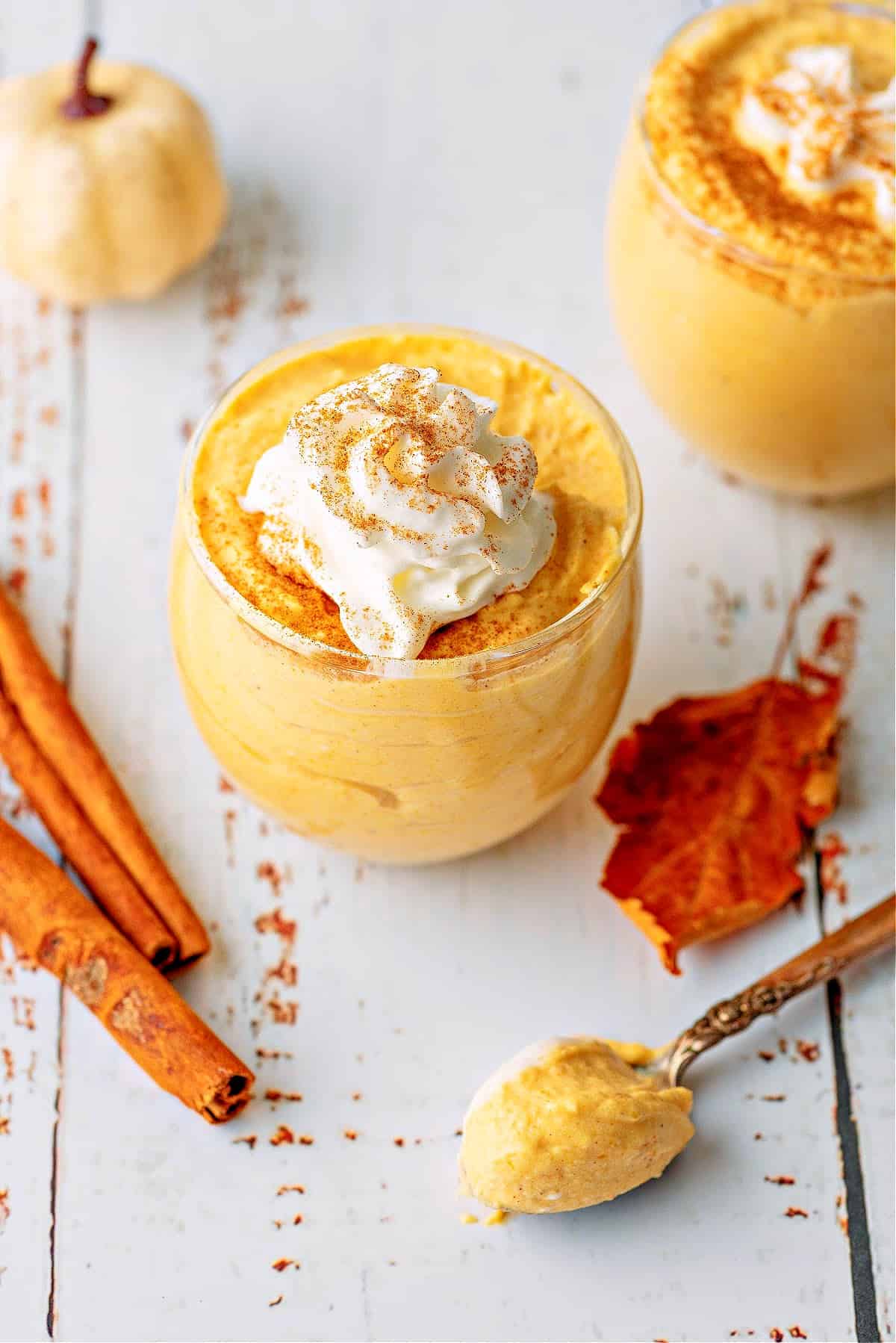 two glass cups of keto pumpkin mousse with cinnamon sticks