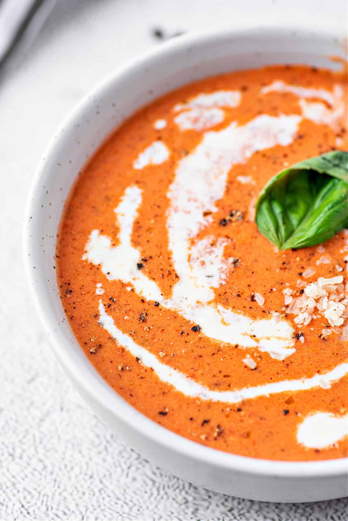 a bowl of tomato soup with cream and basil on top