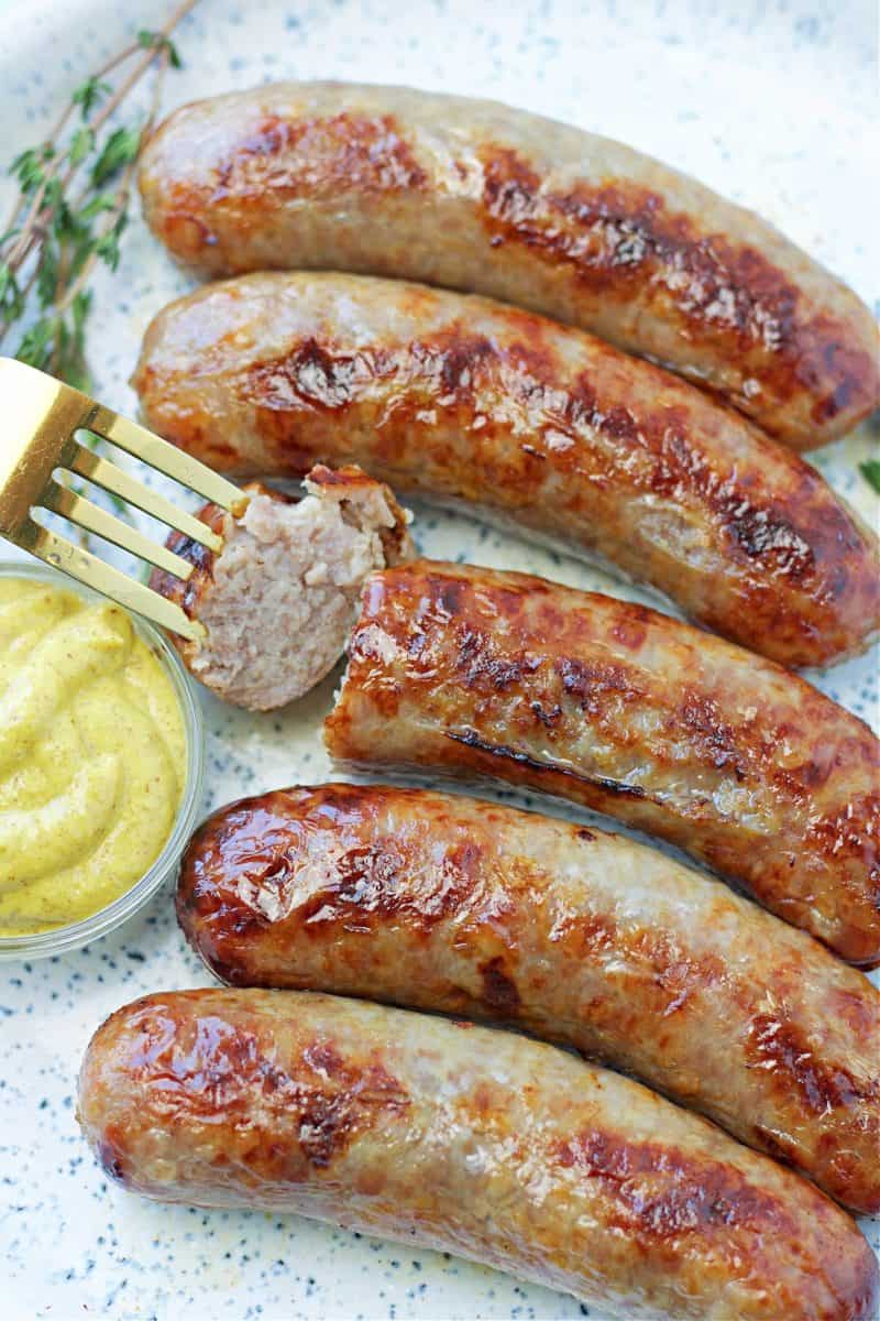 a plate of air fryer brats on a plate with dijon mustard