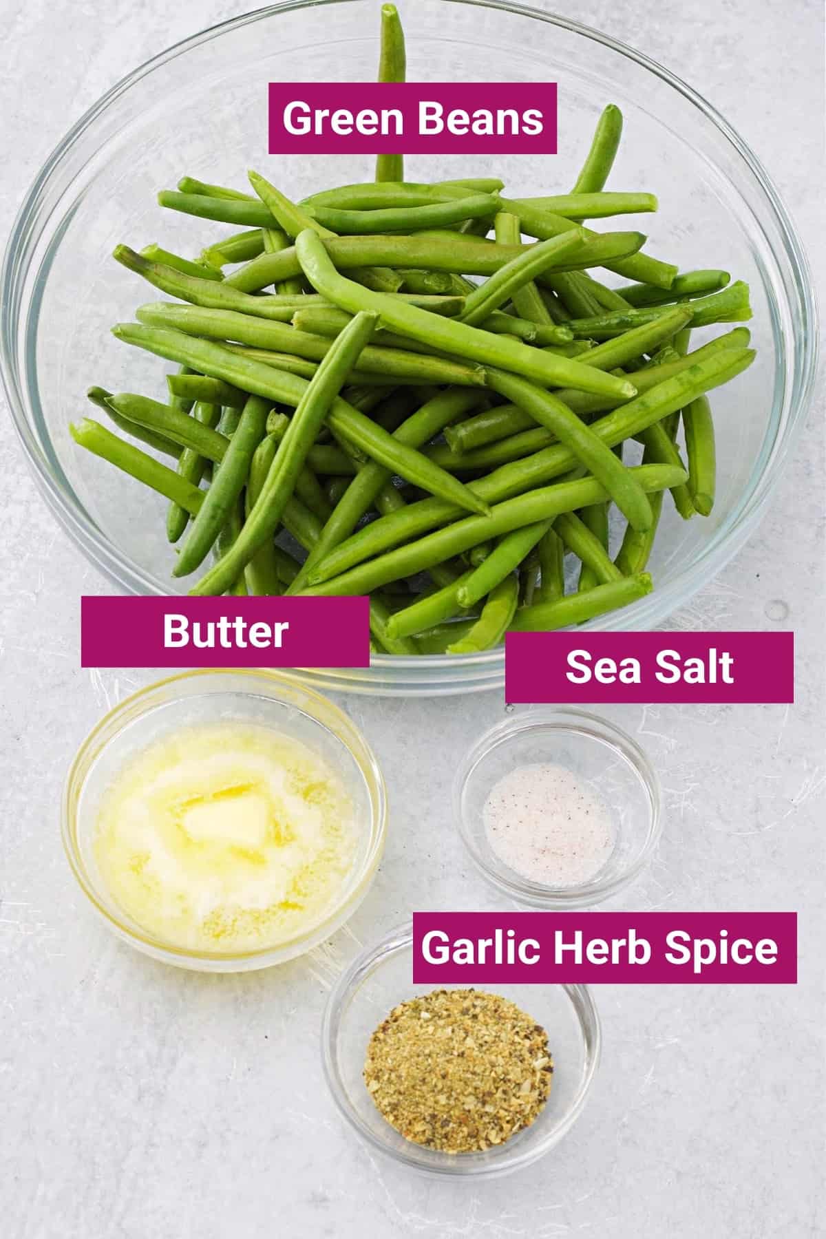 ingredients needed to make air fryer green beans: fresh trimmed green beans, melted butter, sea salt, and garlic and herb seasoning in separate bowls
