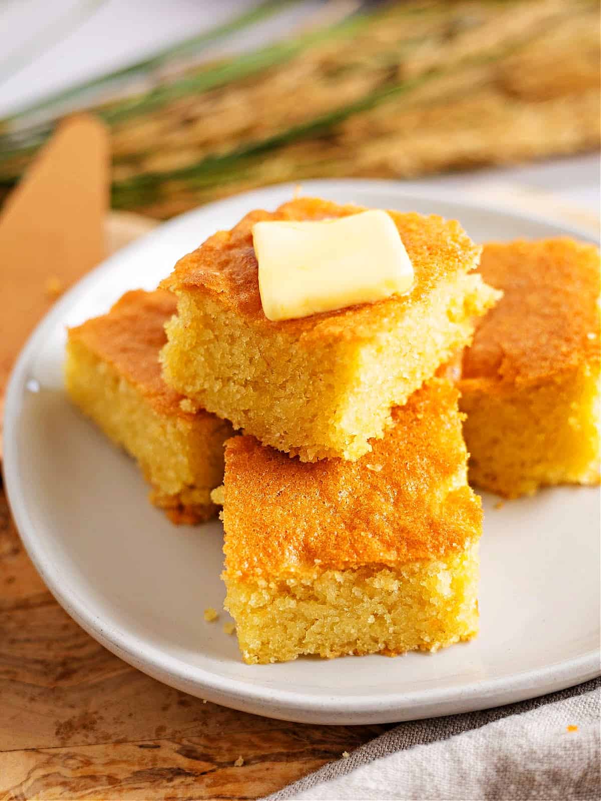 slices of keto cornbread stacked on a plate with butter