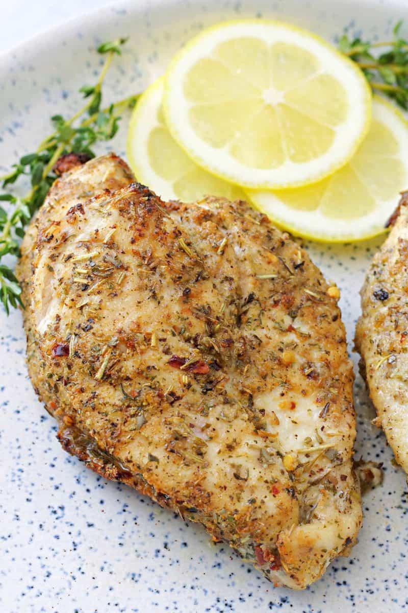 whole air fried chicken breast on a plate with lemon slices