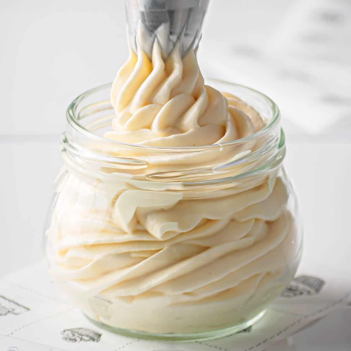 a close up of low carb cream cheese frosting being piped into a glass jar