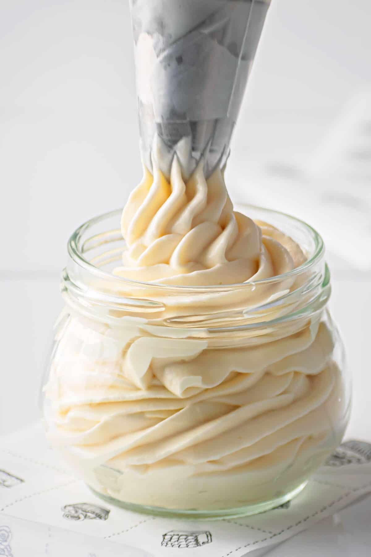 keto cream cheese frosting being piped into a glass jar