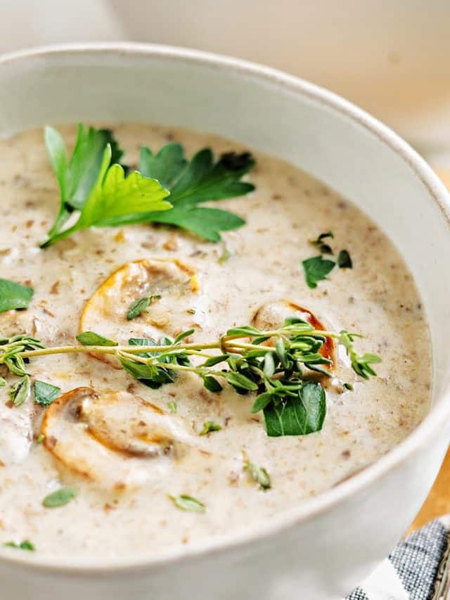a bowl of homemade cream of mushroom soup topped with mushrooms and parsley