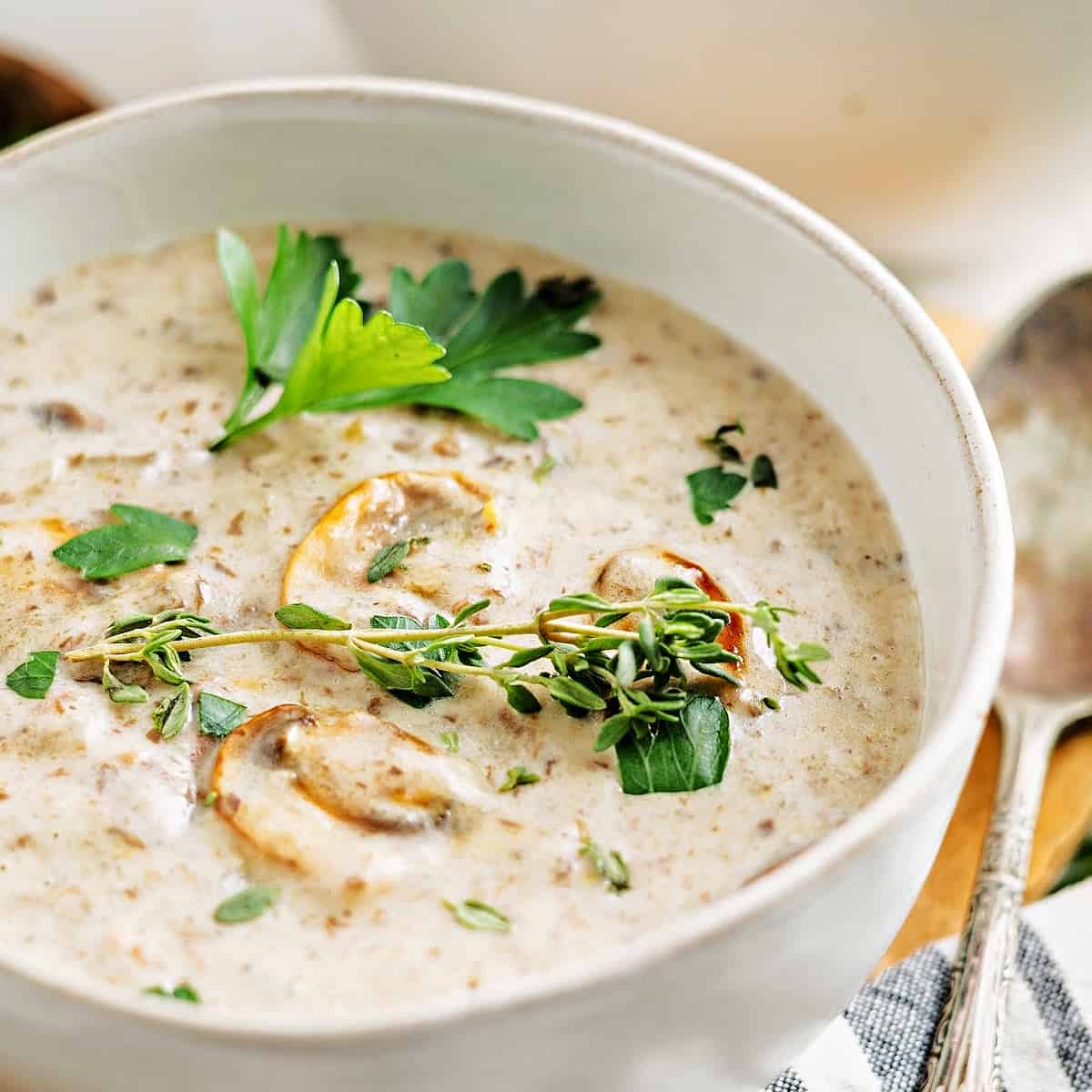 a bowl of homemade cream of mushroom soup topped with mushrooms and parsley