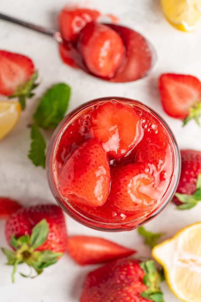 an overhead photo of keto strawberry sauce in a glass jar with lemon slices