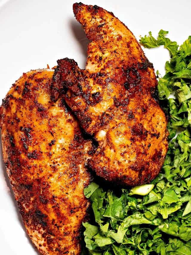 close-up of two dry rub chicken breasts on a plate