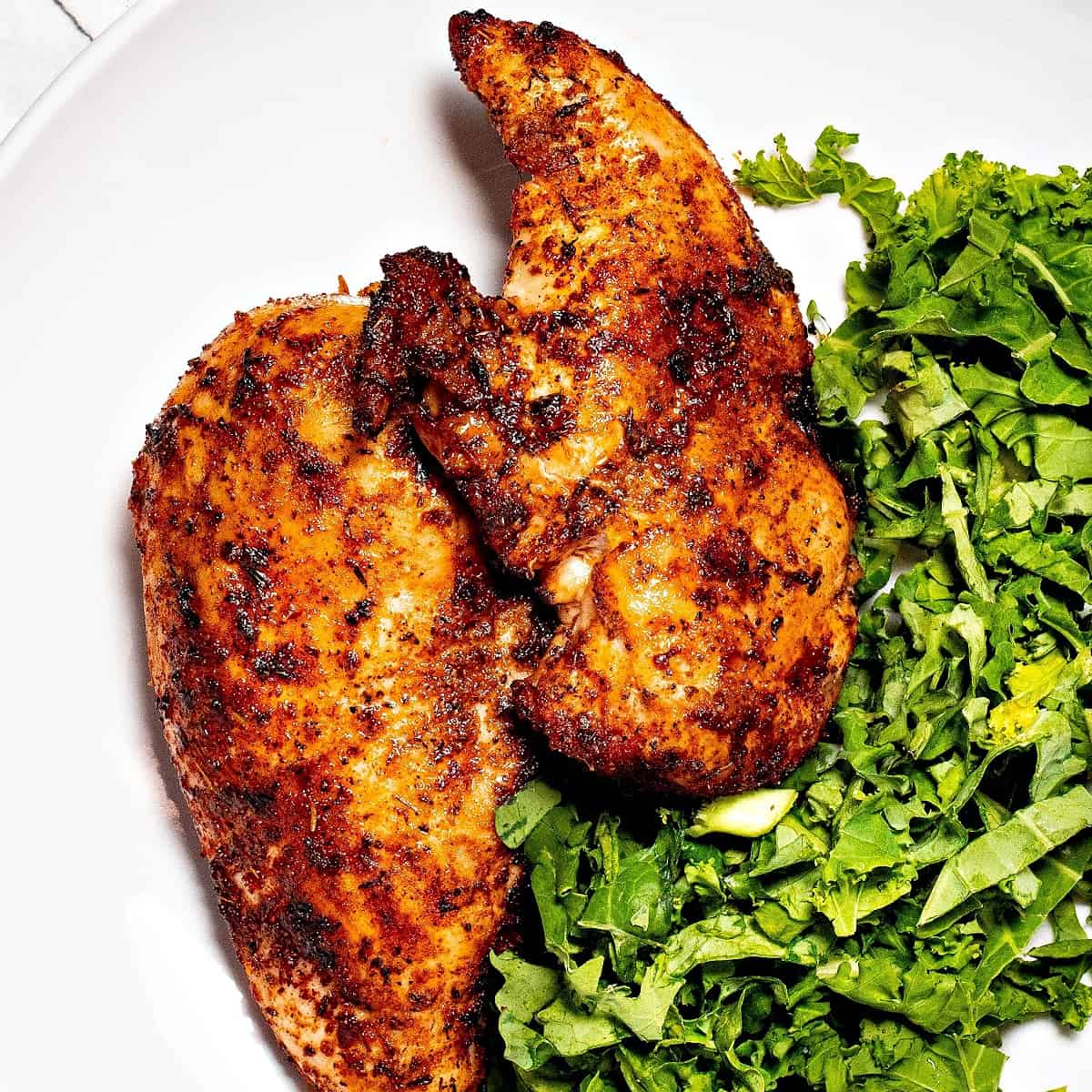 close-up of two dry rub chicken breasts on a plate