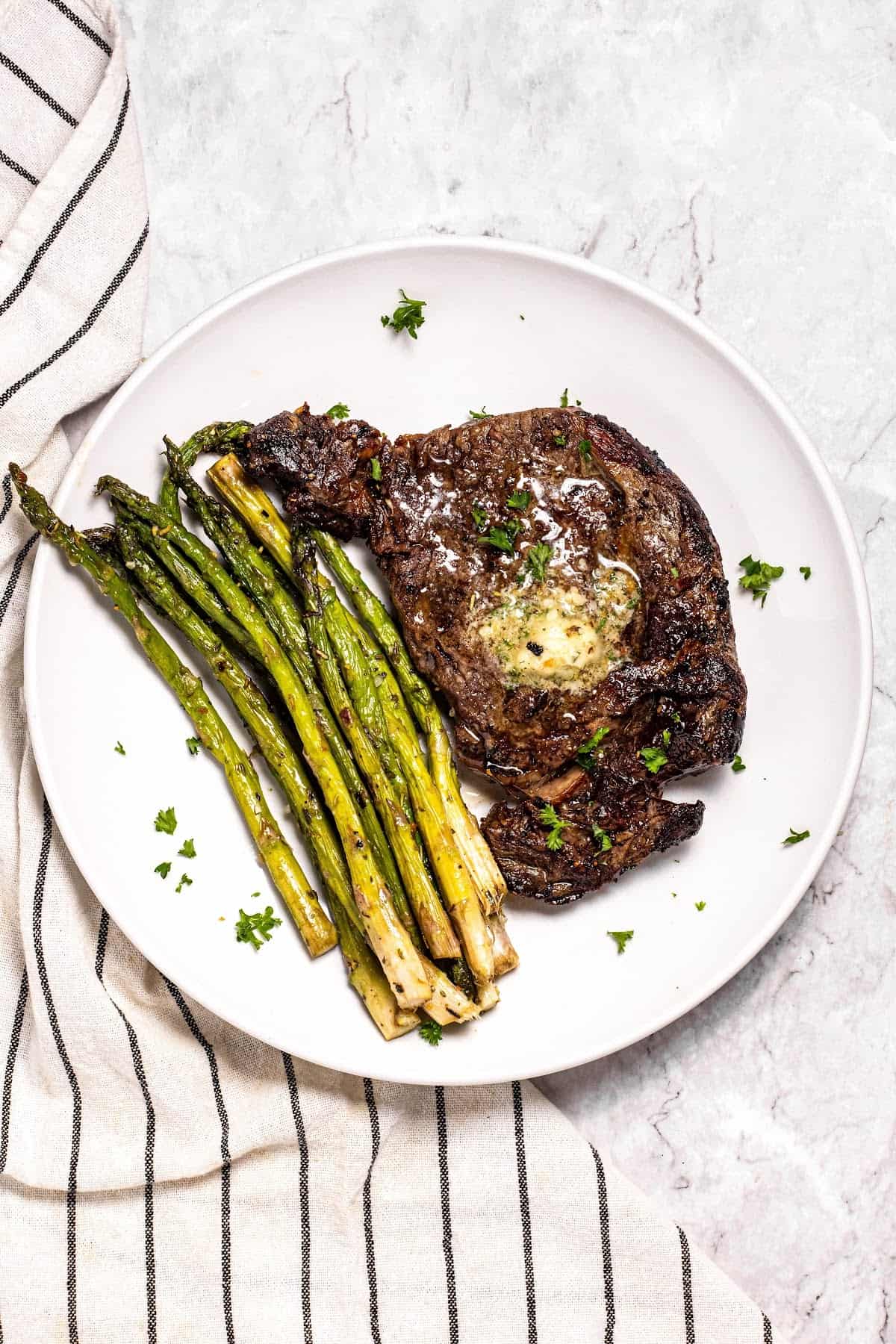 air fryer asparagus on a plate with steak and herb butter